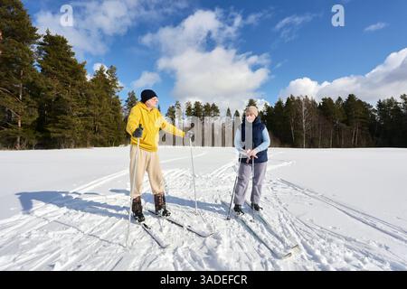 Per una breve pausa dalle escursioni sugli sci attraverso i campi innevati, una coppia europea di mezza età gode di una soleggiata giornata invernale. Foto Stock