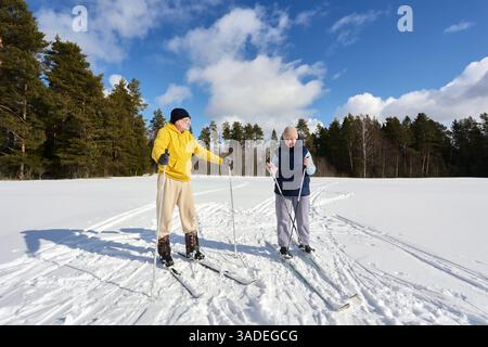 Sciare attraverso il campo innevato ai margini della foresta, la coppia bianca dei 50 anni si è riposata. Foto Stock