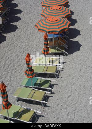 Sdraio e ombrelloni a righe ben allineati su una spiaggia di ciottoli, Monte rosso, cinque terre, Italia, Europa Foto Stock