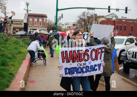 Bloomington, Stati Uniti. 5 aprile 2025. BLOOMINGTON, INDIANA - 5 APRILE: Una donna porta un cartello con scritto "mani fuori dalla nostra democrazia", durante la manifestazione "mani fuori" per manifestare contro il presidente degli Stati Uniti Donald Trump al tribunale della contea di Monroe il 5 aprile 2025 a Bloomington, Indiana. Le proteste contro le politiche amministrative di Trump e il Dipartimento di efficienza del governo (DOGE) di Elon Musk si svolgono a livello nazionale in quella che gli organizzatori chiamano giornata nazionale d'azione. ( Crediti: Jeremy Hogan/Alamy Live News Foto Stock