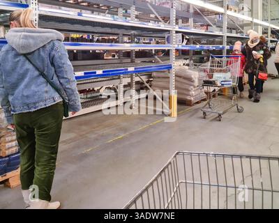 Leopoli, Ucraina - 08 marzo 2022: Scaffale vuoto nel mercato, carrello della spesa. Persone in maschere protettive che cercano cibo nei negozi di alimentari. Pandemia, blocco, e. Foto Stock