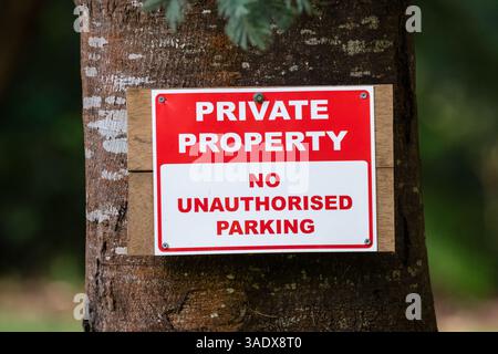 Primo piano di un cartello rosso e bianco "Private Property No Unauthorized Parking" montato su un albero, Tarra Valley, Australia Foto Stock