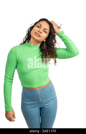 Foto in studio di una giovane donna latina che si tocca i capelli mentre sorride e posa su uno sfondo bianco Foto Stock