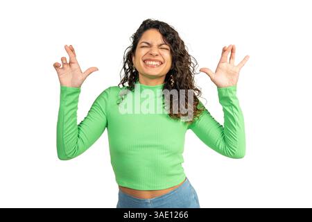 Giovane donna ottimista che incrocia le dita augurando buona fortuna, esprimendo un desiderio con un'espressione allegra Foto Stock