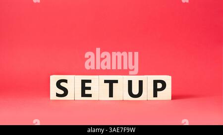 Simbolo di configurazione. Cubi in legno con parola Setup. Bellissimo sfondo rosso. Concetto di installazione. Copia spazio. Foto Stock