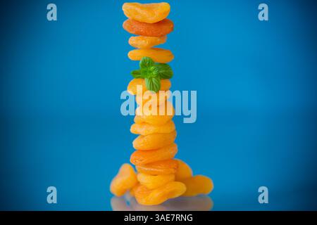 Composizione estetica con albicocche secche e menta fresca su sfondo blu. Foto Stock