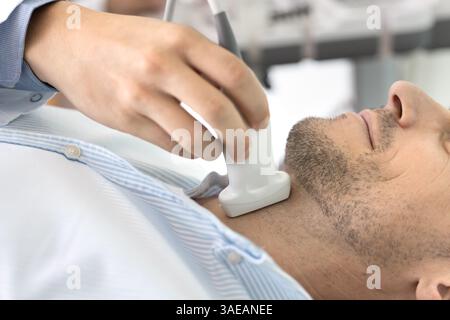 Primo piano di un maschio sottoposto a esame ecografico della tiroide in clinica Foto Stock