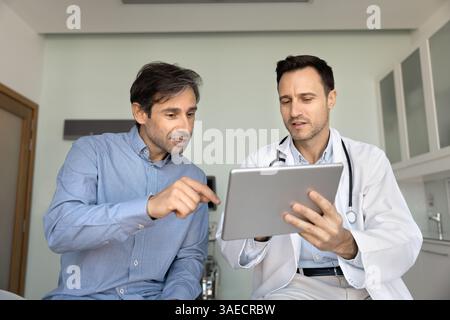 Medico che spiega le informazioni al paziente su tablet digitale Foto Stock