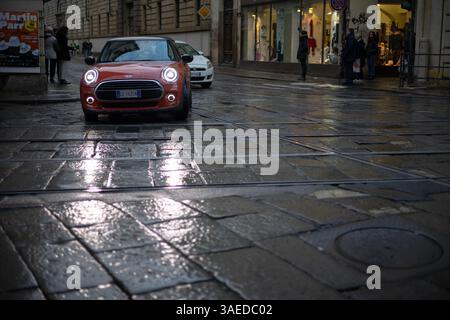 Torino, Italia - 08 novembre 2021: Una Mini Cooper rossa parcheggiata su una strada acciottolata bagnata vicino a una Fiat bianca Foto Stock