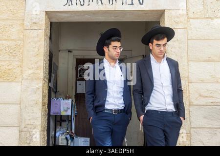 Haifa, Israele, 5 aprile 2025, Tiferet Israel Yeshiva. Due giovani ebrei ortodossi in abiti e cappelli in piedi davanti a una porta Foto Stock