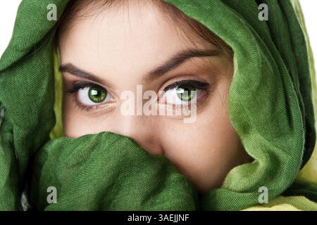 Ritratto di misteriosa bella ispanica caucasica Latina donna faccia verde con occhi penetranti e moda verde sciarpa avvolta attorno alla testa e mout Foto Stock