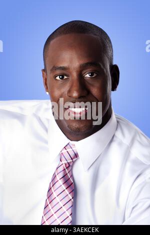 Faccia del bello felice African American business aziendale uomo sorridente, indossa una camicia bianca e rosa con strisce cravatta su un cielo blu-come backgroun Foto Stock