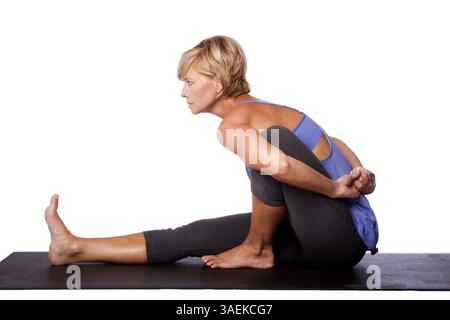 Bella donna in posizione seduta spinale Twist Marichyasana yoga pose stretching gambe e spinale esercizio, isolato, Atlanta, Stati Uniti, Nord America Foto Stock