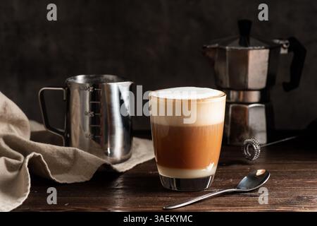 Tè e latte tailandese caldo con schiuma di latte nel bicchiere. Foto Stock