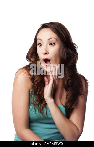 Espressione facciale di una giovane donna sorpresa e sorpresa con la mano sul mento e lunghi capelli marroni ondulati, isolati, Atlanta, Stati Uniti, Nord America Foto Stock