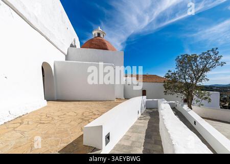 Vista della famosa chiesa di Puig de Missa con pareti bianche e cupola rossa sotto il vibrante cielo blu con nuvole a Ibiza, Spagna. Foto Stock