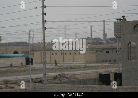 13 aprile 2005; AR Ramadi, Iraq; Un Marine con 2nd Squad, 2nd Platoon, compagnia C, 1st Battalion, 5th Marine Regiment, posta la sicurezza dal tetto di un edificio, mentre i Marines pattugliano le strade sottostanti. Marine con 2nd Squad, 2nd Platoon, compagnia C, 1st Battalion, 5th Marines, pattugliavano un quartiere noto come ÒGhettoÓ dove distribuivano caramelle ai bambini e opuscoli di propaganda positivi e anti-insorti agli uomini iracheni. Credito obbligatorio: Foto di Cpl. Tom Sloan/DOD/ZUMA Press. (©) Copyright 2005 di US DOD Photo Foto Stock