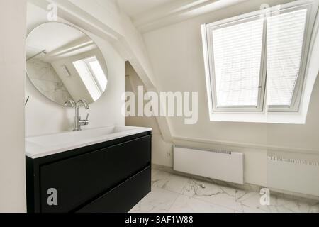 Un bagno elegante ed elegante con un elegante lavandino, specchio ed elementi di design minimalista con accenti in marmo. Foto Stock
