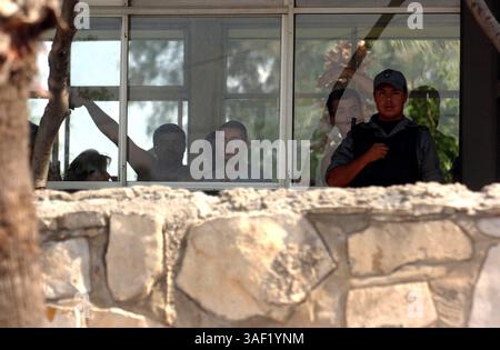 27 giugno 2005; Nuevo Laredo , MESSICO; Una guardia pesantemente armata controlla le vittime salvate dei rapimenti a Nuevo Laredo. Sono detenuti in una struttura dell'esercito messicano. Le loro famiglie e i loro amici attendono con ansia il loro ritorno. Credito obbligatorio: Foto di Billy Calzada/San Antonio Express-News/ZUMA Press. (©) Copyright 2005 di Billy Calzada/San Antonio Express-News Foto Stock