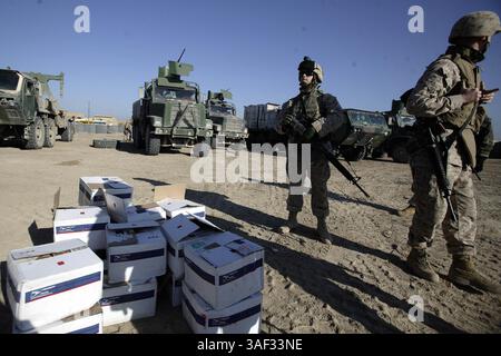 21 dicembre 2004; Fallujah, Iraq; Two Marines with Combat Service Support Company 115 aspettano che gli altri Marines finiscano di scaricare la posta da un camion da 7 tonnellate prima di trasportare i pacchi ai Marines presso il Civil Military Operations Center di Fallujah, Iraq, 21 dicembre 2004. Il CSSC-115 di Camp Pendleton, California, parte del 1st Force Service Support Group, è responsabile della fornitura di provviste, come cibo, acqua, munizioni e carburante, alle unità marine che operano a Fallujah e nelle sue vicinanze. A novembre, il CSSC-115 di Camp Pendleton, California, ha registrato più di 31.000 miglia di tempo su strada a sostegno di Foto Stock