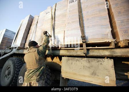 21 dicembre 2004; Fallujah, Iraq; Marine Cpl. MARC C. WARD, un operatore di veicoli militari con Combat Service Support Company 115 e 21 anni nativo di Bellevue, Wash., stringe le cinghie su pallet di cibo posti sul retro di un camion da 7 tonnellate prima di dirigersi su un convoglio a Fallujah, Iraq, 21 dicembre 2004. L'unità di Camp Pendleton, California, facente parte del 1st Force Service Support Group, è responsabile della fornitura di provviste, come cibo, acqua, munizioni e carburante, alle unità marine che operano a Fallujah e nelle sue vicinanze. A novembre, il CSSC-115 di Camp Pendleton, California, ha registrato più di Foto Stock