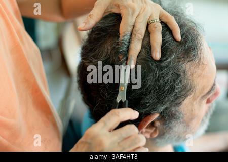 Uomo anziano che si fa tagliare i capelli dalla moglie anziana a casa Foto Stock
