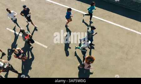 Un gruppo diversificato di persone partecipa a una gara all'aperto, mostrando energia e spirito comunitario. Acquisita dall'alto, l'immagine evidenzia il movimento. Foto Stock