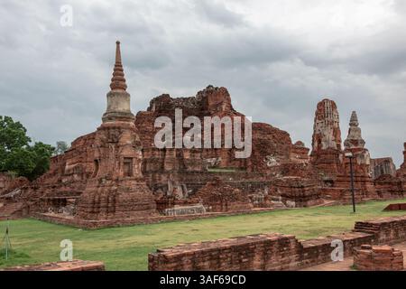 Edificio in rovina di mattoni rossi e templi in pietra, complesso di pagoda di Wat Phra si Sanphet, sito storico Ayutthaya in Thailandia, in una giornata nuvolosa Foto Stock
