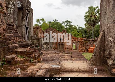 Complesso di rovine di templi in pietra rossi e mattoni, struttura storica di Angkor Wat nella lussureggiante foresta verde di Siem Reap, Cambogia Foto Stock