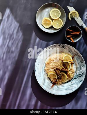 Classico budino di riso cremoso decorato con bastoncini di limone e cannella a fette su sfondo grigio. Luce del mattino Foto Stock