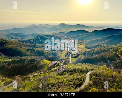 Vista aerea di un'alba su un paesaggio di valle italiana tra colline e montagne in primavera con una strada tortuosa che porta in lontananza Foto Stock