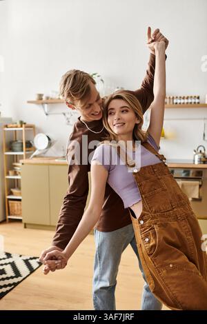 Una coppia amorevole balla gioiosamente nella loro elegante cucina, creando un'atmosfera calda e romantica. Foto Stock