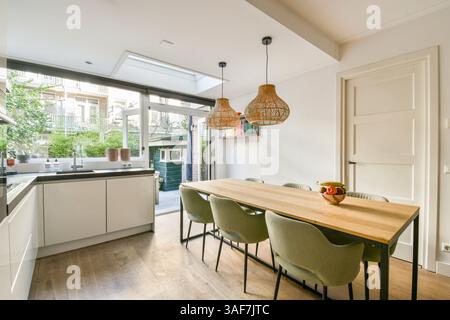 Una cucina elegante e moderna con elementi di design minimalisti, luce naturale e un invitante spazio da pranzo con eleganti posti a sedere. Perfetto per un soggiorno contemporaneo. Foto Stock