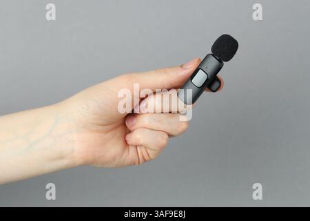 Donna con microfono lavalier su sfondo grigio chiaro, primo piano Foto Stock