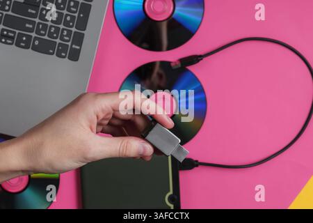 La mano femmina tiene un'unità flash USB sullo sfondo dei gadget. Vista dall'alto Foto Stock