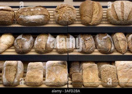 Vari tipi di pane tradizionale fatto in casa sugli scaffali in legno di un negozio di panetteria e sullo sfondo di una panetteria astratta Foto Stock
