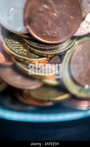 Monete di diverse valute raccolte in un vaso di vetro Foto Stock
