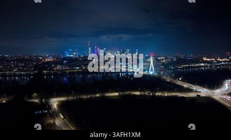 Un paesaggio notturno mozzafiato di Varsavia: Il ponte Świętokrzyski, i grattacieli e le strade illuminate d'oro che si estendono all'orizzonte. Foto Stock