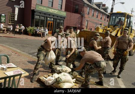 Le truppe della Guardia Nazionale dell'Esercito del Maryland caricano sacchi di sabbia usati su un caricatore da rimuovere dal molo di City nel centro di Annapolis, sabato 20 settembre 2003. Nel retroterra la gente siede in bar che proprio ieri sono stati bloccati dall'acqua inondata. I residenti e i proprietari di affari ripuliscono i loro negozi al City Dock nel centro di Annapolis dopo l'inondazione dell'uragano Isabel che ha chiuso il quartiere storico. (Immagine di credito: The Washington Times/ZUMAPRESS.com) Foto Stock