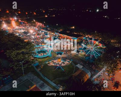 Vista aerea di un vivace carnevale notturno nelle Filippine, che mostra giostre colorate, luci luminose e affollate, catturate con un drone Foto Stock