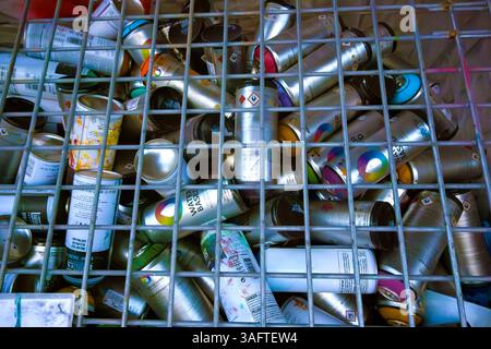 Bombolette spray usate sotto una griglia metallica Foto Stock