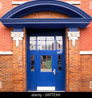 Audace ingresso blu adagiato su una facciata in mattoni rossi con dettagli di colonne bianche e una sporgenza ad arco a Chicago Foto Stock