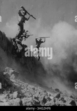 Le lezioni della campagna papuana sono state imparate a fondo dai Commandos ora addestrati in Australia. I primi elementi essenziali sono la robustezza, la capacità di resistere alle difficoltà e i nervi dell'acciaio. Per aggiungere un tocco di realismo, una miniera di terra è appena esplosa dietro queste truppe mentre saltano giù da un fiume hank lungo 20 metri durante le manovre a Victoria. 13 febbraio 1943. Foto Stock