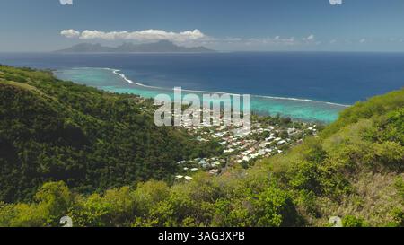 Vista aerea dell'isola tropicale di Tahiti con lussureggianti colline verdi della foresta, laguna turchese, barriera corallina, piccole case costiere nel canyon di montagna. Viaggi esotici remoti nella Polinesia francese Foto Stock