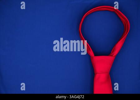Immagine simbolica di una cravatta rossa a forma di anello. Politica commerciale americana, pressione economica, tariffe e strategia politica. Minimalismo. Copia spazio. Foto Stock