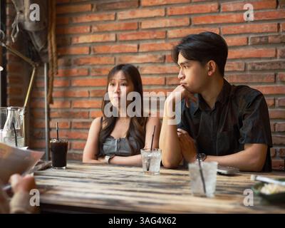 Amici asiatici che mangiano insieme al ristorante mentre discutono e combattono Foto Stock