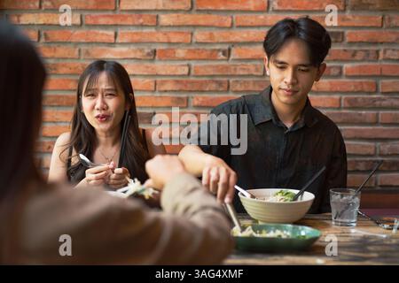 Amici asiatici che mangiano insieme al ristorante e si divertono Foto Stock