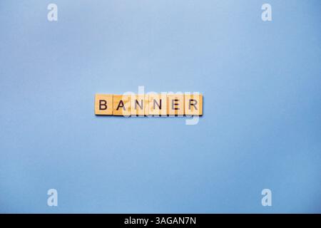 I blocchi di legno scrivono il BANNER su uno sfondo azzurro. Foto Stock