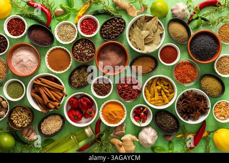 Un variopinto assortimento di spezie ed erbe fresche e profumate, esposte su un morbido sfondo verde, catturando una brillante essenza culinaria Foto Stock