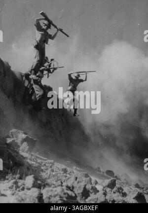 Le lezioni della campagna papuana sono state imparate a fondo dai Commandos ora addestrati in Australia. I primi elementi essenziali sono la robustezza, la capacità di resistere alle difficoltà e i nervi dell'acciaio. Per aggiungere un tocco di realismo, una miniera di terra è appena esplosa dietro queste truppe mentre saltano giù da un fiume hank lungo 20 metri durante le manovre a Victoria. 13 febbraio 1943. Foto Stock